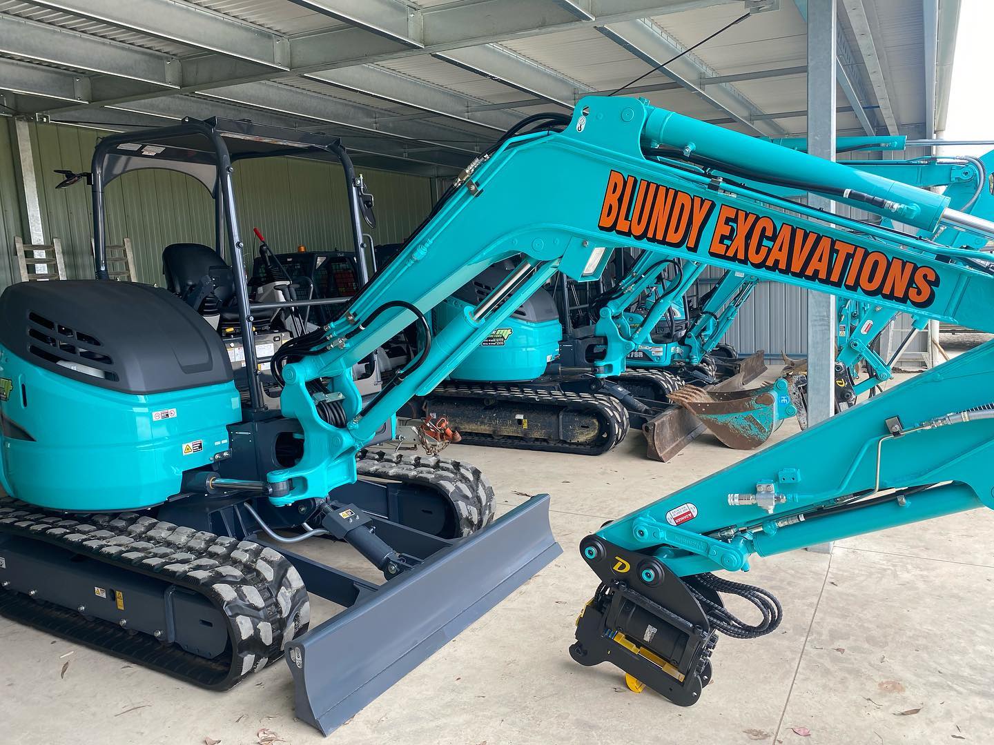 Blue excavators in a storage facility.