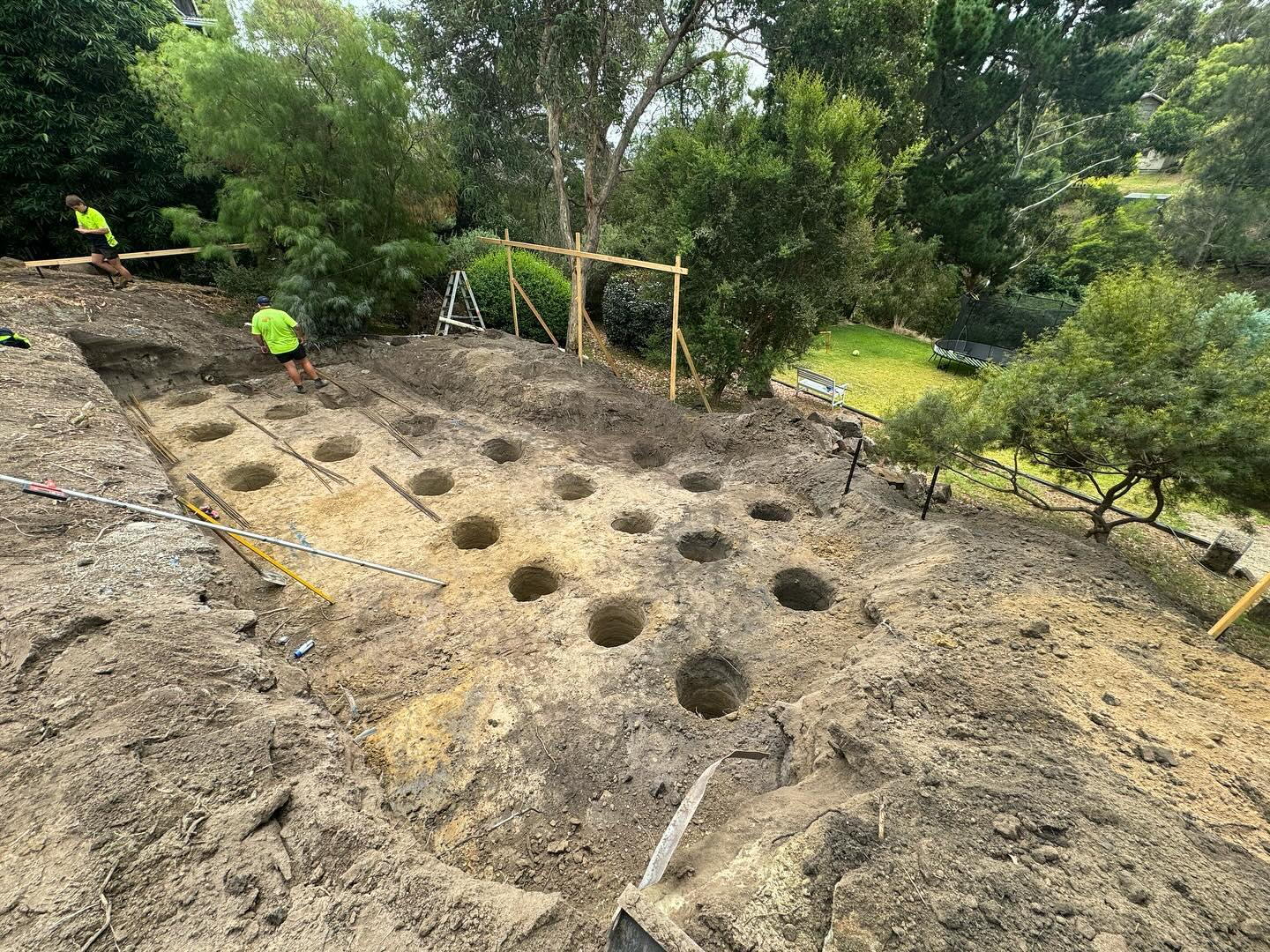 Workers preparing ground with holes for construction.