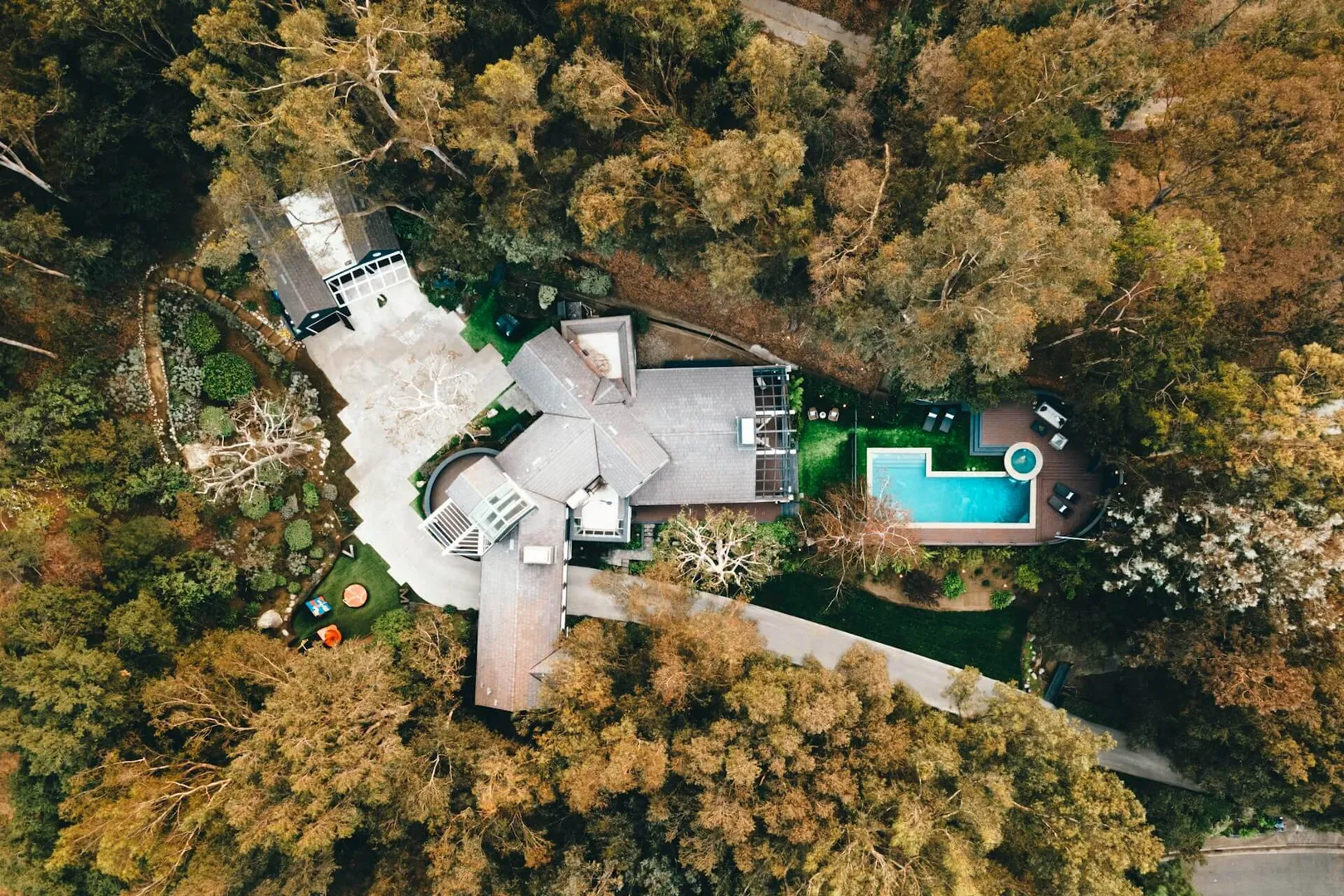 Aerial view of a house with pool in forest.